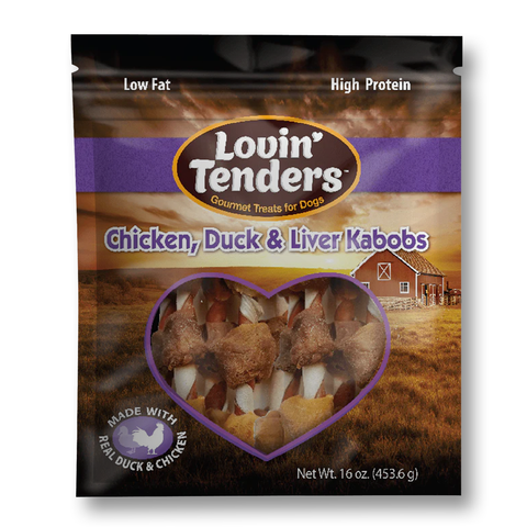 A 16 oz bag of Lovin' Tenders Chicken, Duck & Liver Kabobs dog treats, featuring a heart-shaped window that displays the cooked meat and vegetables inside. The packaging has a rustic farm background with a red barn and features purple and brown color blocks with the brand logo.