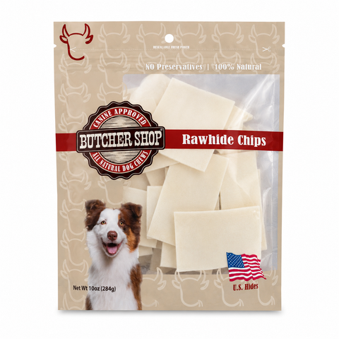 A package of butcher shop rawhide dog chips, featuring a beige stand-up pouch with a dog illustration, a red logo banner, and a clear window showing the off-white rectangular rawhide chips inside.