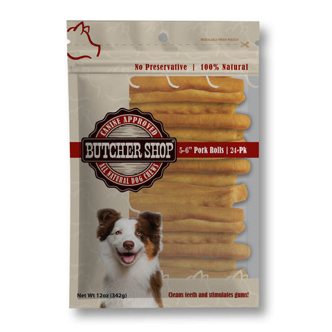 A package of butcher shop natural dog treats, featuring pork rolls visible through a clear window on the front of the beige resealable bag. The packaging includes a butcher shop logo, a dog illustration, and text indicating 5-6" pork rolls and 24-pk.