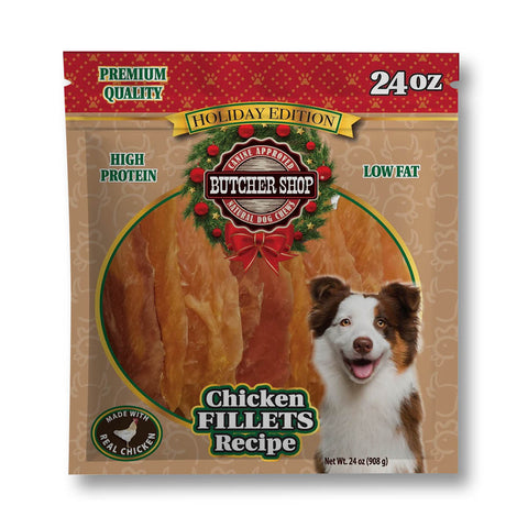 A 24 oz bag of Butcher Shop Holiday Edition Chicken Fillets Recipe dog treats, featuring a brown package with red holiday accents, a circular window showing the golden-brown fillets, and a smiling dog on the front.