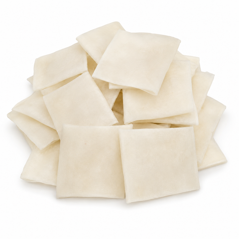 A pile of square, off-white dog chews stacked on a plain white background.