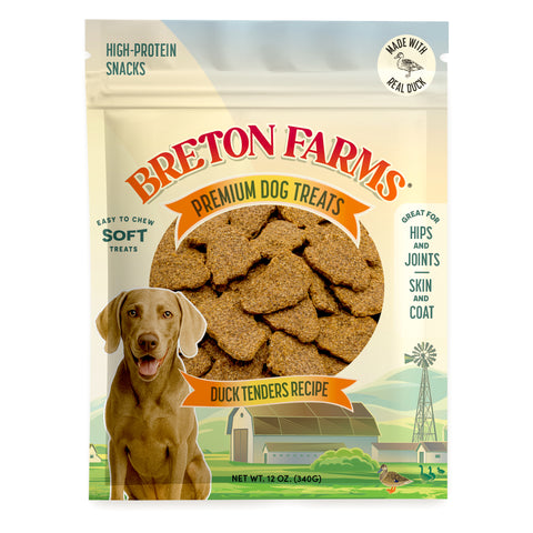 A 12 oz bag of Breton Farms Premium Dog Treats (Duck Tenders Recipe) featuring a brown retriever illustration, a circular window showing the dog treats inside, and a green farm illustration at the bottom.