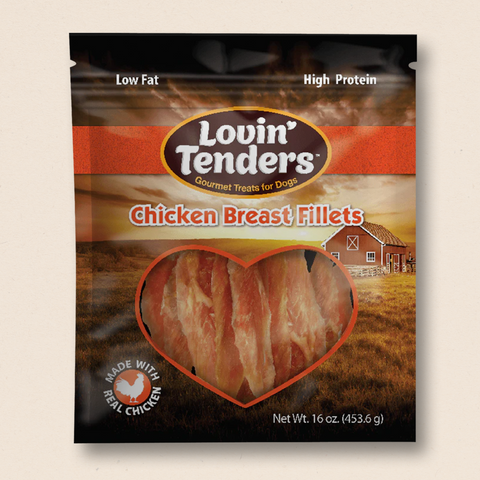 A package of Lovin' Tenders Chicken Breast Fillets dog treats, featuring a heart-shaped window showing the raw meat inside, set against a scenic farm background on the package.